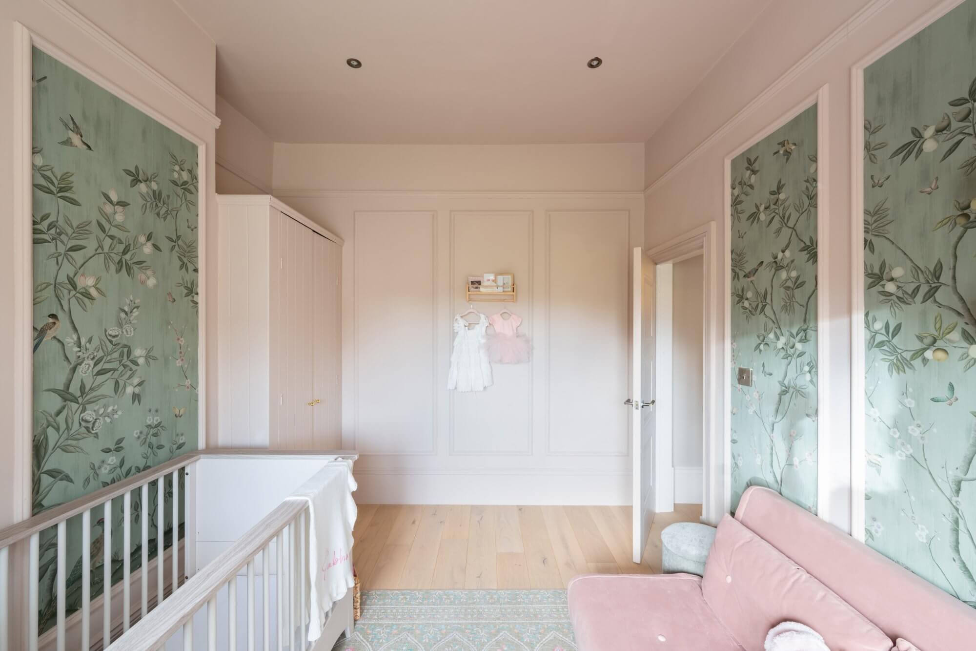 Nursery with hand-painted wallpaper panels and pink velvet sofa bed